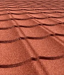 Red Decra metal roofing with textured, scalloped tile design under natural light. - Asia Jaya Sepadu.