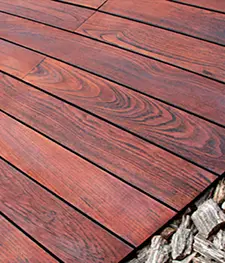 Outdoor timber decking with rich reddish-brown wooden planks and visible natural wood grain pattern. - Asia Jaya Sepadu.